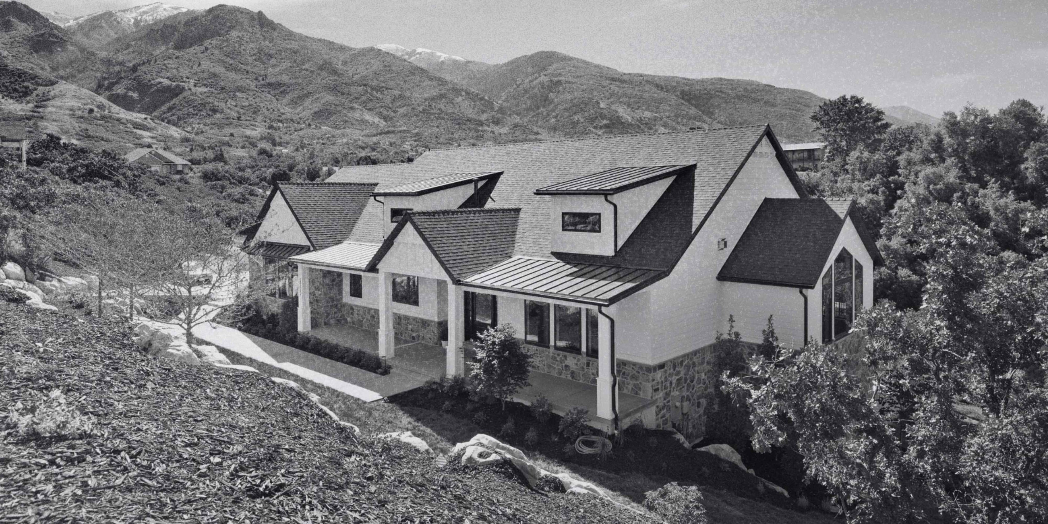 Modern custom home with stone accents, white siding, covered porches, and dramatic mountain views.