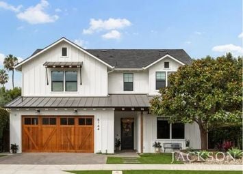 Two-story farmhouse-style home with white siding, wood garage doors, black trim, and a covered front entry.
