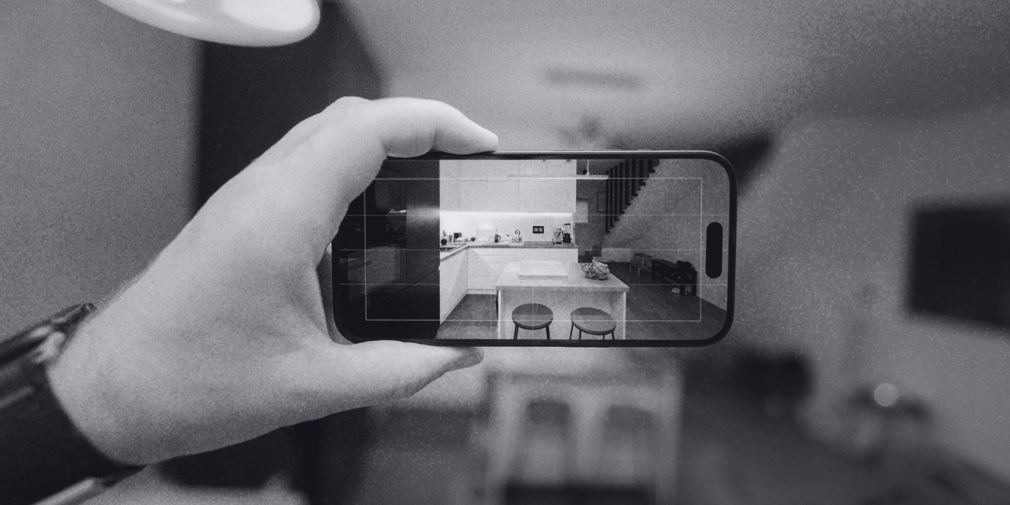 Hand holding a smartphone to photograph a remodeled kitchen interior.